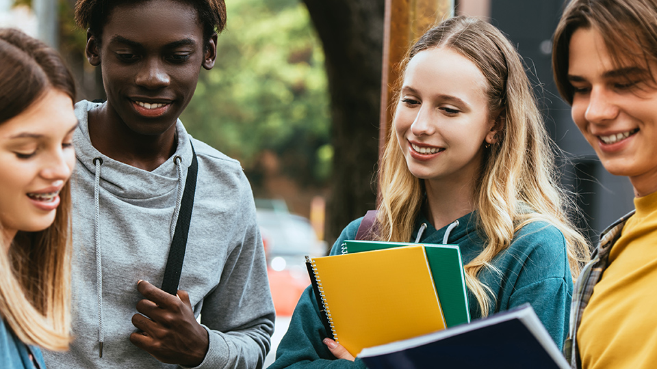 Fyra gymnasieelever som står och pratar utanför skolan.