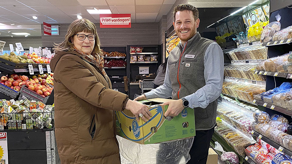 Agneta Wallander, enhetschef på kostenheten på Vänersborgs kommun tar emot en låda av Christoffer Russo, ägare av ICA Älgen i Vargön.