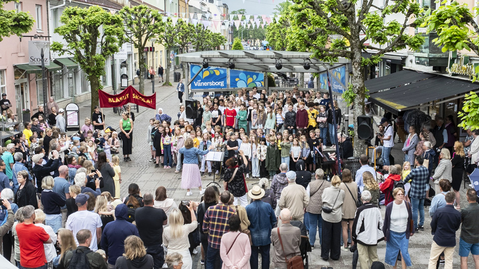 En stor barnkör omgiven av mängder av åskådare på gågatan i Vänersborg.