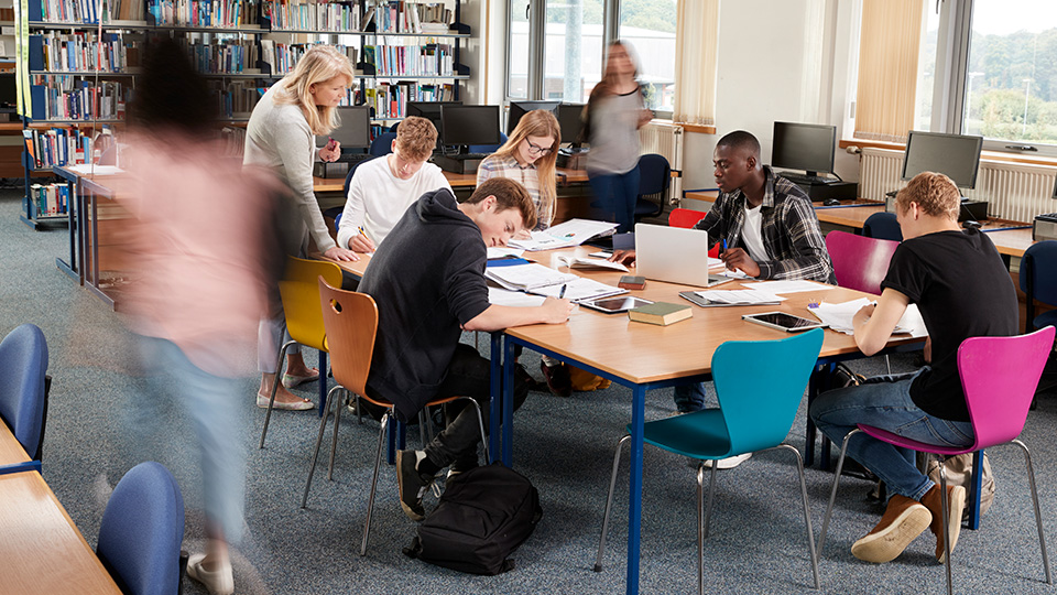 Studenter sitter och pluggar i ett högskolebibliotek.