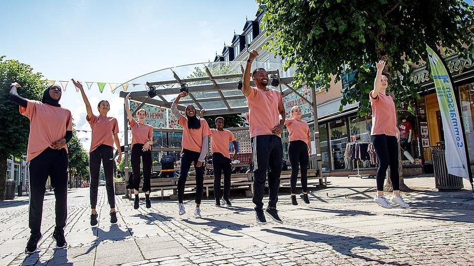 Sommardansare i laxrosa T-shirts hoppar synkront i ett somrigt Gågatekryss