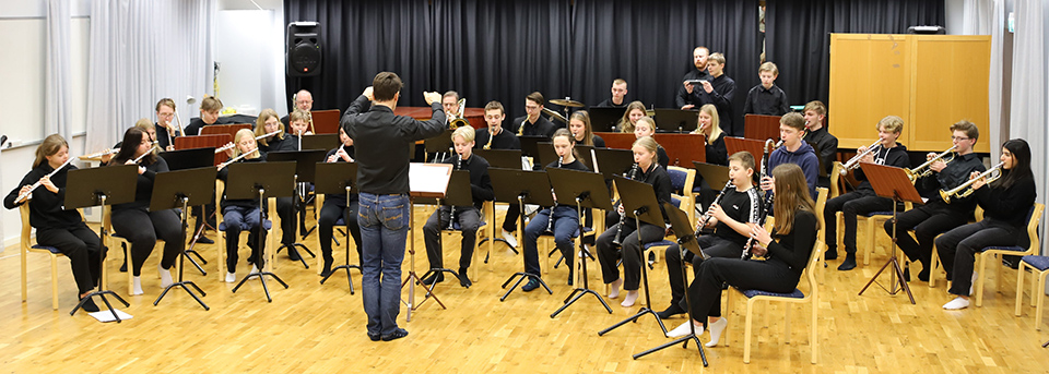 Stråkorkester spelar på golvet i en aula.