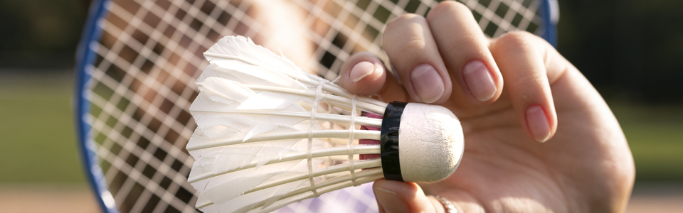 En person håller upp en fjäderboll till badminton.