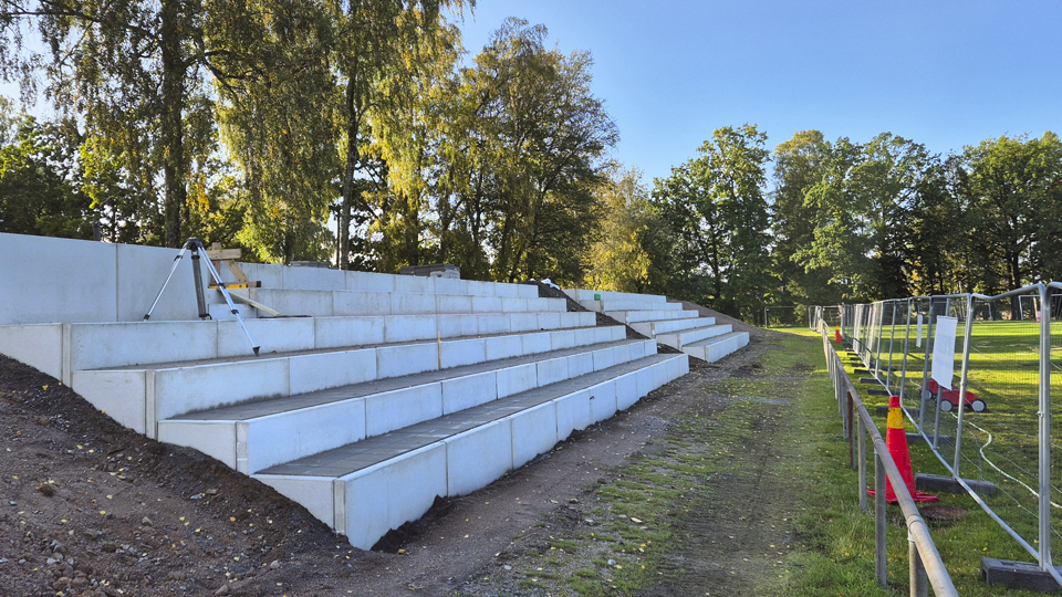 Läktare av betong håller på att byggas vid fotbollsplanen.