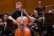 Ung kille spelar cello med orkesterkomp