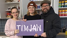 Timjans personal står och håller en lila skylt med Timjans logotyp.