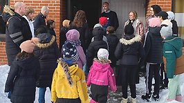 Samling utanför entrén med barn i mössor och vinterjackor. 